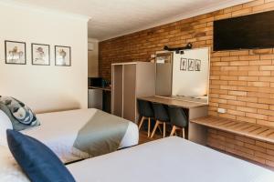 a hotel room with two beds and a desk with a tv at Oasis Motor Inn Blackall in Blackall