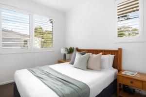 Un dormitorio con una cama blanca con dos ventanas. en Penthouse with Incredible Views & Pool, en Noosa Heads 13 fotos más