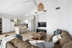 Una sala de estar con un sofá y una cocina. en Penthouse with Incredible Views & Pool, en Noosa Heads