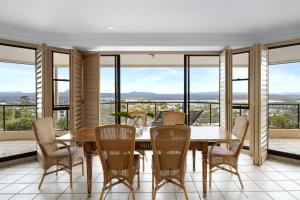 a dining room with a table and chairs and large windows at Belle De Jour, Penthouse 5, Noosa Heads in Noosa Heads