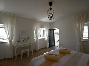 a white bedroom with a bed and a mirror at House Palma in Selca