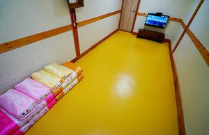 a small room with a yellow floor and a laptop at Jeonju Hanok Village Beautiful Garden House in Jeonju