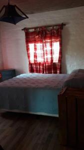 - une chambre avec un lit doté d'un rideau rouge et d'une fenêtre dans l'établissement Punta Negra-disfrutable todo el año, à Maldonado