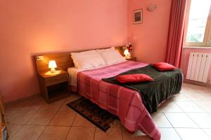 a bedroom with a bed with a red blanket and a table at Affittacamere La Rosa in Lucca