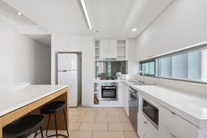 a kitchen with white counters and a large window at Quattro Apartments in Brisbane