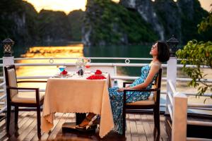 una mujer sentada en una mesa frente a una fuente en Swan Cruises Halong, en Ha Long