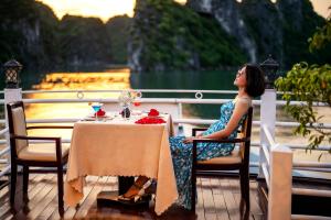 una mujer sentada en una mesa frente a una fuente en Swan Cruises Halong en Ha Long