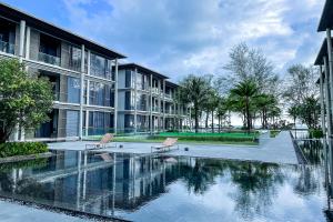 two chairs sitting next to a swimming pool in a building at Baan Mai Khao - 2 Bedroom Luxury Condo - Direct Pool & Beach Access in Mai Khao Beach