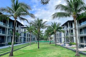 a courtyard with palm trees in front of a building at Baan Mai Khao - 2 Bedroom Luxury Condo- Direct Pool & Beach Access in Mai Khao Beach