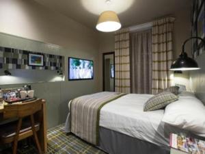 a bedroom with a bed and a desk and a television at Jolly's Hotel Wetherspoon in Dundee