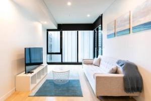 uma sala de estar com um sofá e uma televisão de ecrã plano em Lovely One Bedroom + Study with Infinity Pool em Sydney
