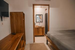 Un dormitorio con una cama y un baño con lavabo. en El Habita CASA SHAKO, en Santa Teresa Beach