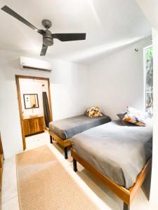 Un dormitorio con dos camas y un ventilador de techo. en El Habita CASA SHAKO, en Santa Teresa Beach