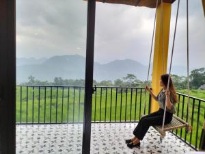 Làng Bang的住宿－Pu Luong May Home & Cafe，坐在秋千上的女人,看着窗外