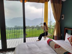 a woman sitting on a swing in a bedroom at Pu Luong May Home & Cafe in Làng Bang