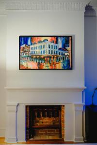a painting of a white building hanging over a fireplace at Royal Frenchmen Hotel and Bar in New Orleans
