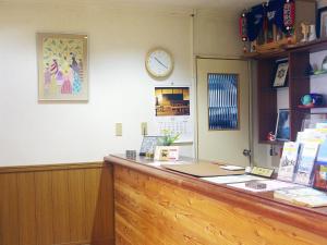 un comptoir de réception avec une horloge sur le mur dans l'établissement olive no sato vingh four eyes shodoshima / Vacation STAY 79057, à Kusakabe