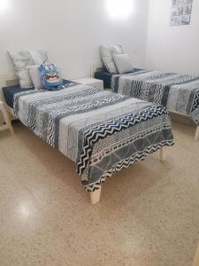 2 letti in una camera con coperte blu e grigie di Écrin a Sousse