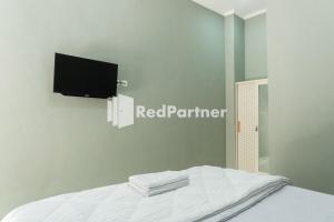 a bedroom with a bed with a tv on the wall at Athena House Syariah Near The Park Mall Solo Baru Mitra RedDoorz in Sukoharjo