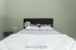 a bed with white sheets and white pillows at Athena House Syariah Near The Park Mall Solo Baru Mitra RedDoorz in Sukoharjo +14 photos