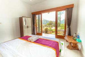 a bedroom with a large bed and a window at Break Villa Kintamani by ecommerceloka in Kintamani