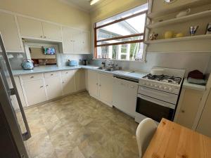 a kitchen with white cabinets and a stove top oven at Seapoint in Point Lonsdale +13 photos