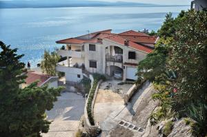a house on a hill with the ocean in the background at Apartments Goran - 150m from sea in Brela