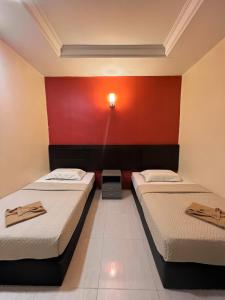 duas camas num quarto com uma parede vermelha em Chuu Pun Village Resort em Pantai Cenang