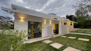 a white house with a lawn in front of it at Tiny Houses en Asunción. Zona Aeropuerto-Rakiura in Zarate Isla