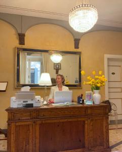 una mujer sentada en un escritorio con un portátil en Palazzo Mari suite & rooms b&b, en Montevarchi