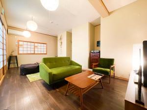 sala de estar con sofá verde y mesa en Suzuki Guesthouse en Kioto