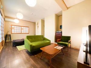a living room with a green couch and a table at Suzuki Guesthouse in Kyoto