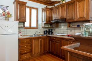 a kitchen with wooden cabinets and a white refrigerator at Kouvlaki Effie's Place in Afissos in Afissos +24 photos