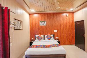 a bedroom with a large bed with a wooden wall at FabExpress Limewood in Dehradun
