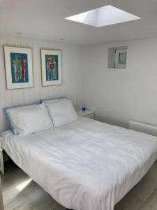 a white bed in a bedroom with two pictures on the wall at Beachhouse Stranddistel 100m from the beach in Noordwijk aan Zee