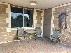 a patio with three chairs and a table and a window at Peaches in Kingscote