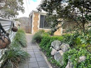 a garden with a stone walkway in front of a house at Peaches in Kingscote
