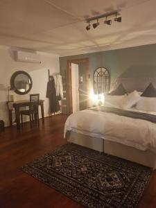 ein Schlafzimmer mit einem Bett und einem Tisch mit einem Teppich in der Unterkunft Meraki Country Manor in Lanseria