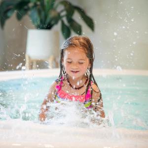 a little girl playing in a swimming pool at Nykščio Namai & SPA in Anykščiai