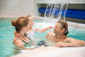 un homme, une femme et une fille dans une piscine dans l'établissement Nykščio Namai & SPA, à Anykščiai