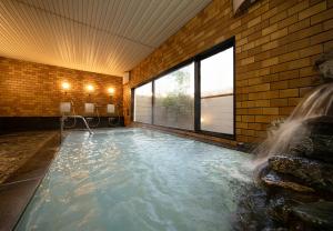 a indoor swimming pool with a waterfall in a building at The Gran Resort Elegante Karuizawa in Karuizawa