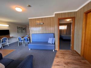 a living room with a blue couch and a table at Sturt Motel Balranald in Balranald