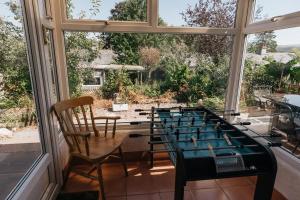 a room with a ping pong table in a window at HILLSIDE COTTAGE - 3 bed property in North Wales opposite Adventure Park Snowdonia in Dolgarrog