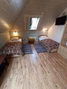 Habitación pequeña con 2 camas y suelo de madera. en Hotel Laagna, en Laagna