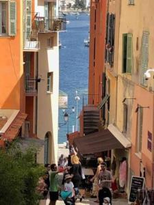 a group of people walking down a street with buildings at Proche mer, vieille ville. Luxueux appartement in Villefranche-sur-Mer