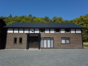 een bruin en wit gebouw met een garage bij 古民家の宿 Solii in Ishikari
