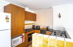 a kitchen with wooden cabinets and a sink at Forestview Apartment Margaret River in Margaret River Town