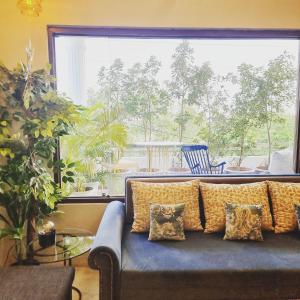 a living room with a blue couch and a large window at Giovanni Suites in Bhopal