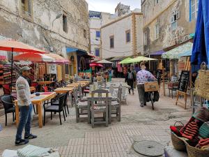 a group of people walking around a street with tables and umbrellas at Riad de charme l'Oasis d'Essaouira - Chambre Luxe in Essaouira