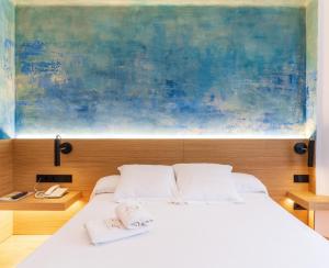 Hotel Rosa & Spa Begur في بيغور: غرفة نوم بسرير ابيض مع لوحة فوقها